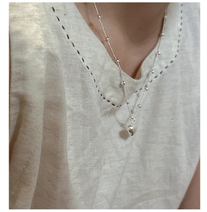 Close-up of s925 silver heart pendant necklace with small beads on a woman's neck