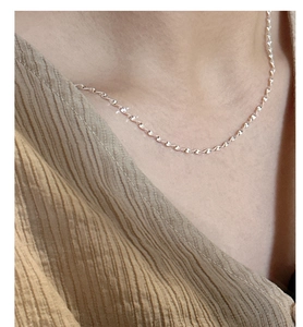 Close-up of minimalist S925 sterling silver shimmering wave chain worn on neckline