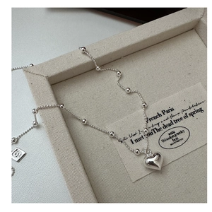 Close-up of a 925 sterling silver heart pendant necklace on a linen jewelry tray