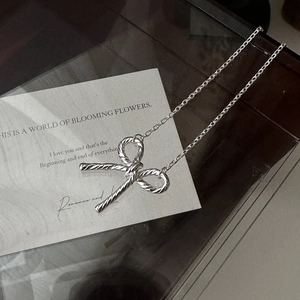 S925 sterling silver bow pendant necklace with twist texture on a vintage wood background