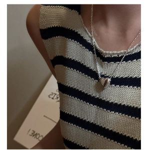 Détail d'un collier pendentif cœur en argent sterling 925 sur un haut à rayures