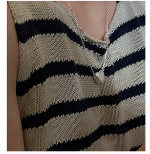 Gros plan d'un pendentif médaillon en cœur argenté sur un pull en maille rayé