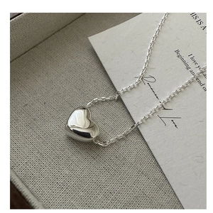 Vue macro d'un pendentif cœur en argent sterling 925 poli sur une chaîne minimaliste