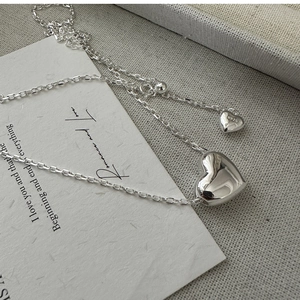 Détail macro de pendentifs cœur en argent S925 avec poinçon sur chaîne minimaliste
