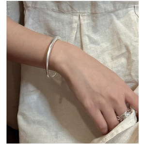Close-up of minimalist S925 sterling silver open bangle and layered ring on model