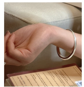 Close-up of minimalist silver cuff bracelet showing polished texture on model wrist