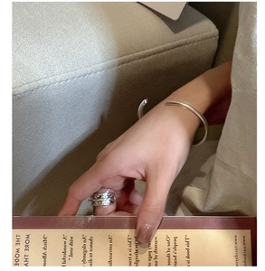 Close-up of a silver open bangle and irregular textured ring on a hand