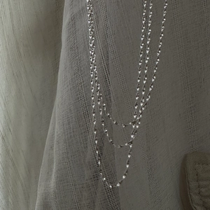 Elegant S925 sterling silver water wave chain necklace draped on a textured fabric base