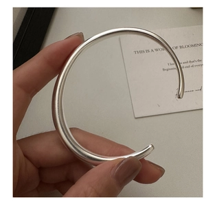 Close-up of minimalist S925 sterling silver open bangle with polished glossy finish