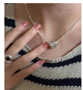 Detail of S925 silver necklace with engraved round pendant and black agate ring on model