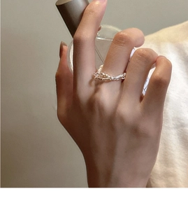 Détail d'une bague double en argent avec perles portée avec un flacon de parfum