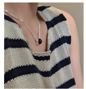 Detail of S925 silver necklace featuring a black onyx pendant on a striped knit top