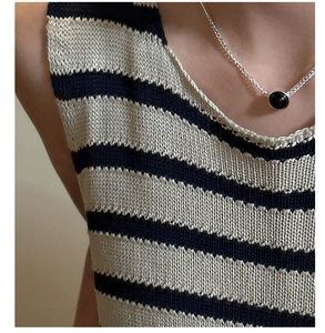 Detail showing an S925 silver necklace with black agate pendant on a knitted top