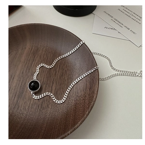 Detail of S925 sterling silver chain with black onyx circular pendant on wood