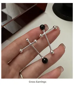 Detail shot of S925 silver cross earrings with black onyx beads held by hand