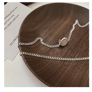Macro detail of S925 sterling silver round pendant with Dream come true engraving on wood