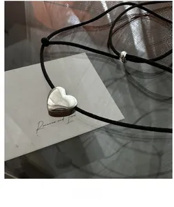 Detailed view of silver heart pendant with adjustable black rope and silver bead