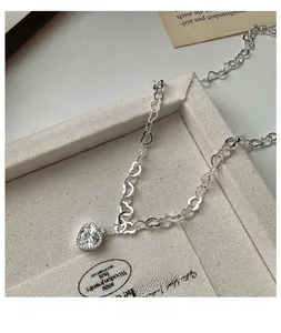 Gros plan du collier coeur en argent S925 avec pendentif zircon sur plateau en toile
