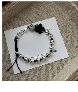 Detail of S925 silver beaded bracelet with black flower and spotted stone on a display card