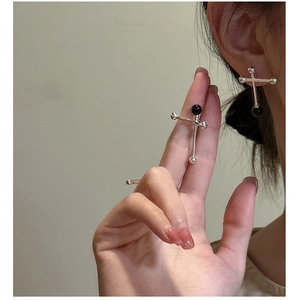 Detail of S925 silver cross earring featuring a black onyx bead on a model's ear