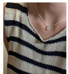 Close-up of minimalist S925 silver necklace with white agate pendant on a model neck