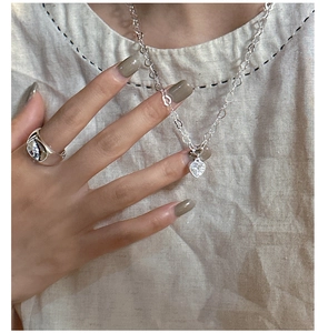 Gros plan sur le collier cœur étincelant et la bague large en argent style liquide