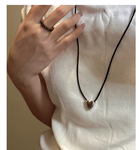 Detail of S925 sterling silver heart pendant on black cord and beaded ring worn by model