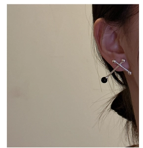 Macro detail of S925 silver cross bar stud earrings with black onyx ball on model