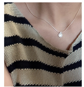 Close-up of S925 silver necklace with a white agate pendant on a striped top