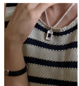 Macro shot of silver woven chain with rectangular black zircon pendant on a neck