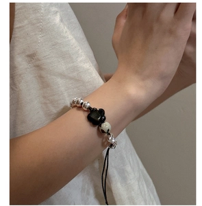 Adjustable silver bead bracelet with a black flower charm and marbled stone on hand