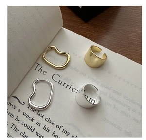 Close-up of minimalist S925 sterling silver rings and earrings on an open book