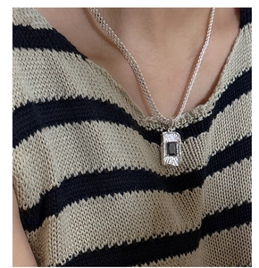 Close-up of woven silver chain with black zircon pendant worn on a striped shirt