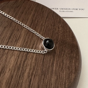 S925 sterling silver necklace with a black agate pendant on a wooden jewelry display