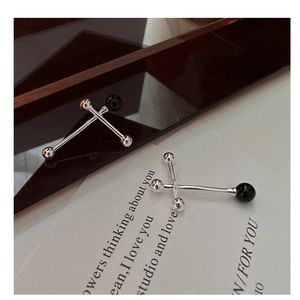 Macro view of minimalist S925 silver cross earrings featuring black onyx balancing beads
