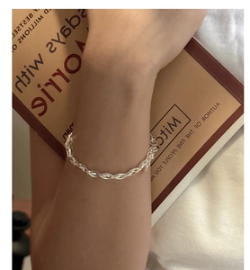 Detail of S925 sterling silver woven chain bracelet on wrist with a book background