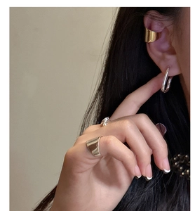 Detail view of stylish S925 sterling silver wave earrings and ring on female model