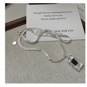 Detailed macro shot of S925 sterling silver woven chain and black rectangle pendant