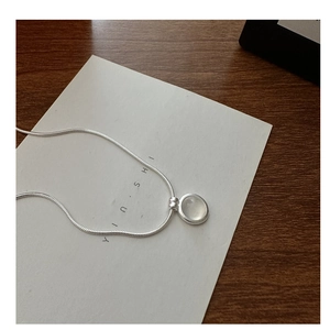 Detailed view of white agate stone pendant on silver snake chain over wooden background