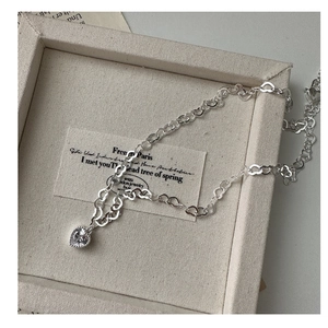 Détail du collier cœur en argent S925 avec zircon dans une boîte à bijoux beige