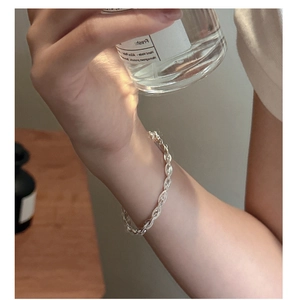 Close-up of minimalist silver twisted rope chain bracelet on wrist with elegant lifestyle decor