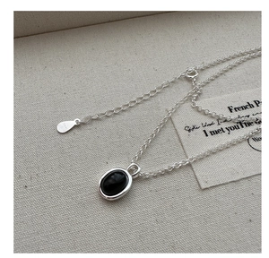 Detailed macro view of S925 sterling silver necklace with oval black agate pendant on canvas