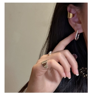 Macro view of polished gold ear cuff and silver ring on model for minimal style