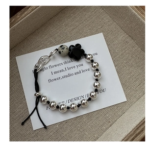 Detail of S925 silver beaded bracelet with black flower charm and adjustable cord strap