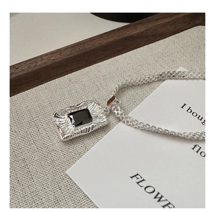 Detailed macro view of silver woven chain necklace with a black zircon gemstone pendant