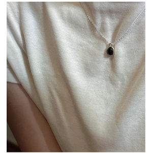 Detail of minimalist S925 silver necklace with round black agate pendant on a model