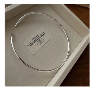 Macro view of minimalist S925 sterling silver hollow choker on a beige fabric tray