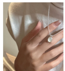Minimalist S925 sterling silver necklace with oval stone pendant on a beige sweater