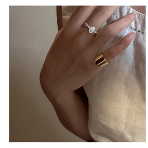 Detail of minimalist gold wide band ring and vintage silver ring worn on model hands