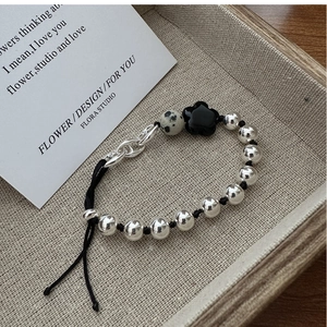 Macro detail of S925 silver beaded bracelet featuring a black flower and spotted stone charm